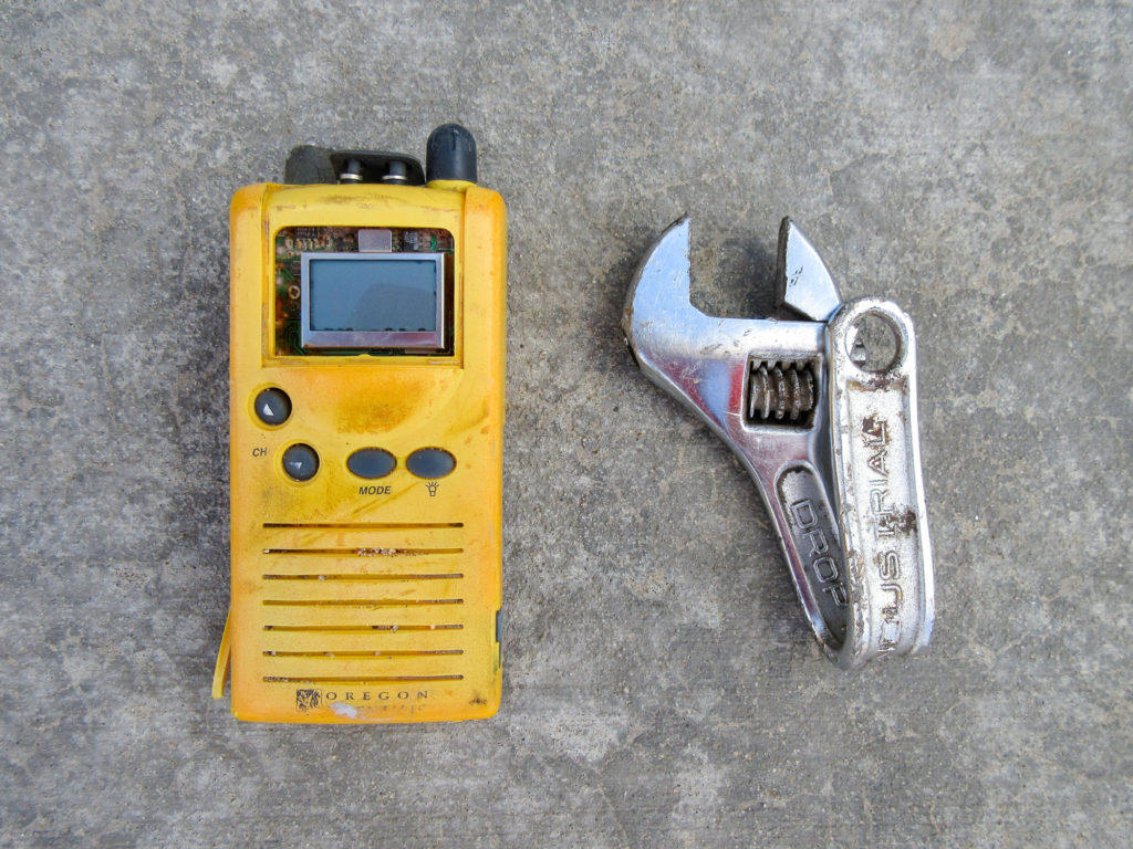 Old, beat up, yellow Oregon Scientific public alert radio and a crescent wrench with the handle folded back on itself
