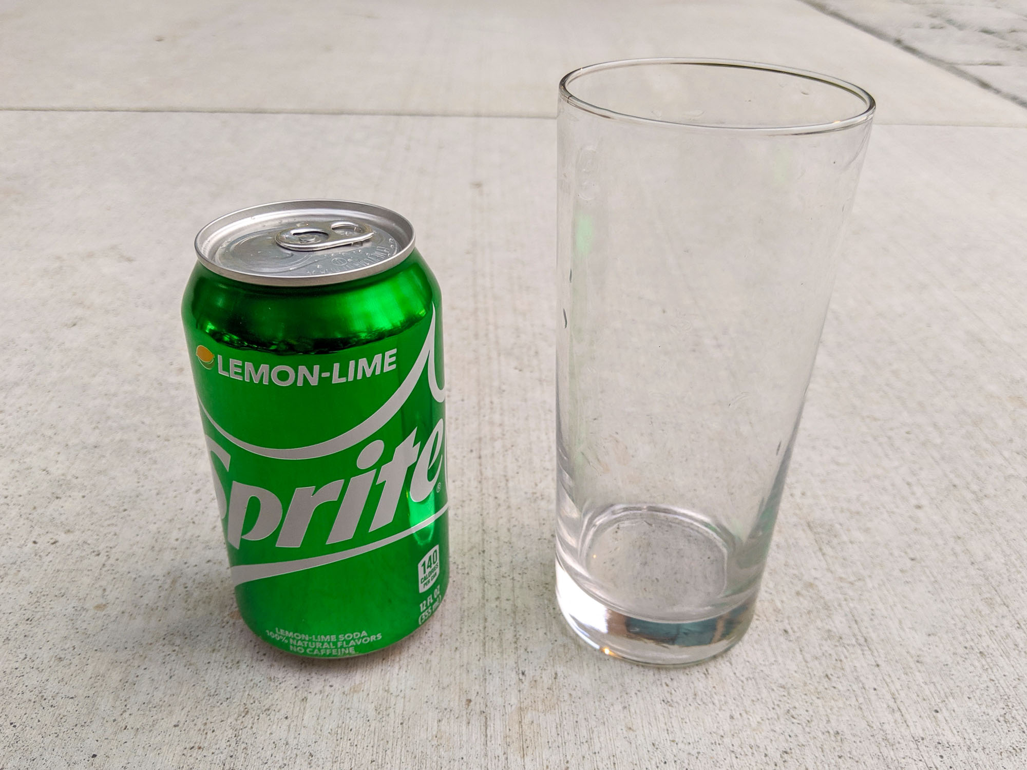 Unopened can of Sprite and glass tumbler