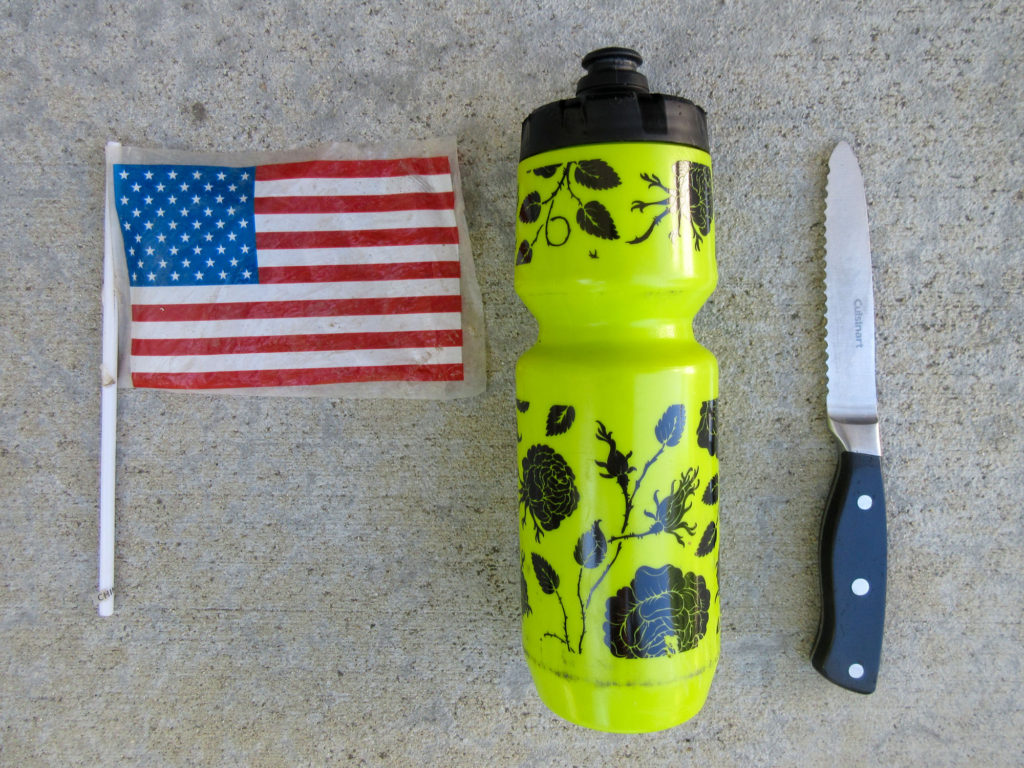 Small plastic U.S. flag, large yellow waterbottle, and Cuisinart steak knife