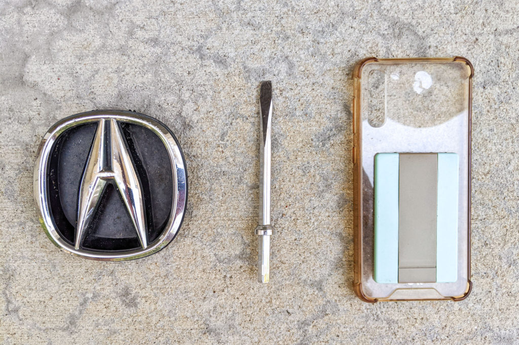 Acura emblem, screwdriver bit, empty phone case
