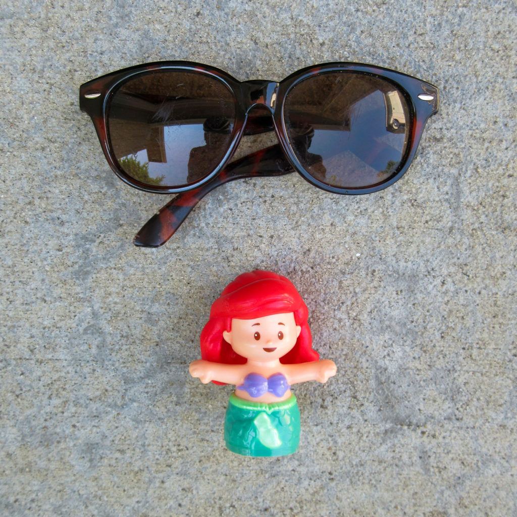 Scartched and bent sunglasses and a Disney's Ariel plastic character