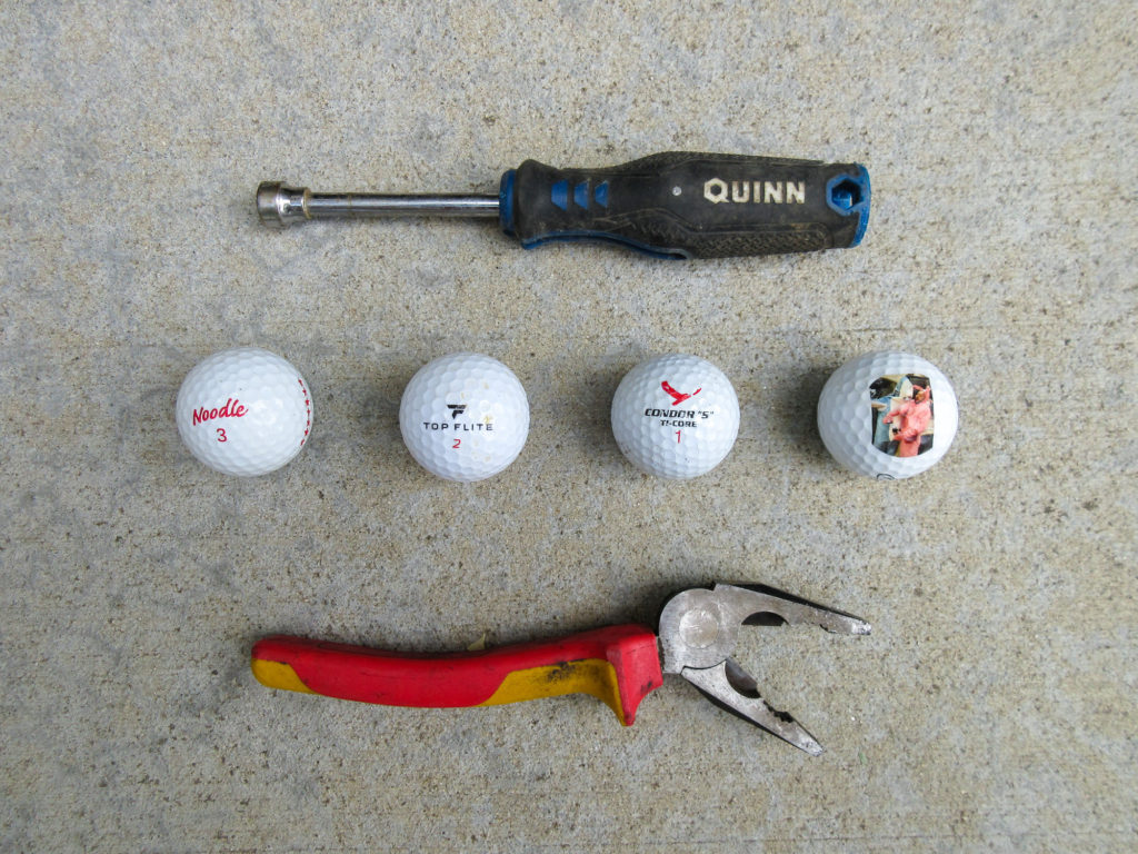 Socket driver, four golf balls, and a pliers missing one of the handles