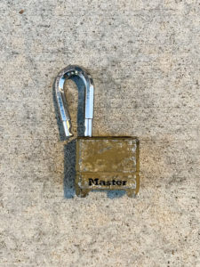 Scratched brass Master lock with a bent shackle in unlocked position