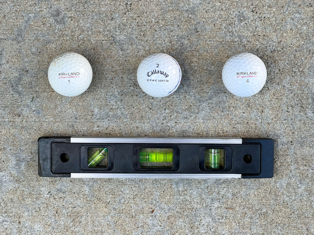 Three golf balls and a torpedo level