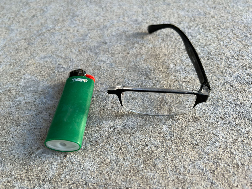 Half a pair of reading glasses and a green BIC lighter