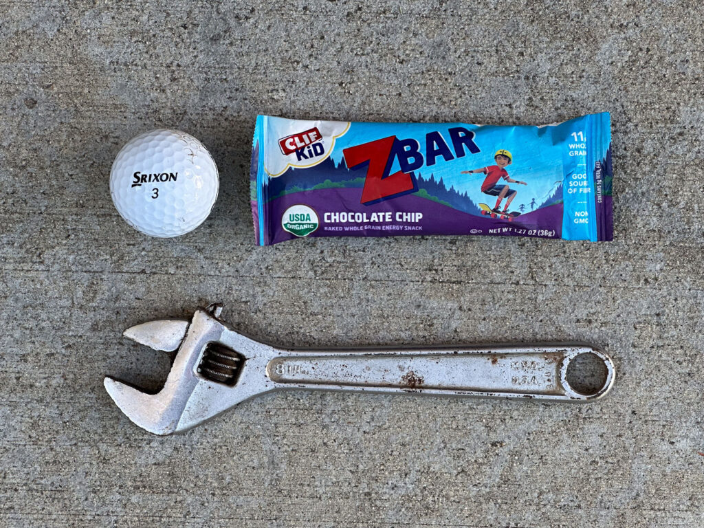 Golf ball, chocolate chip Clif Zbar, and slightly rusty crescent wrench