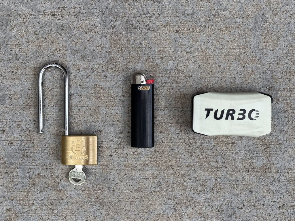 Brinks extended padlock with key, empty BIC lighter, and a battered Viho Turbo disposable vape device