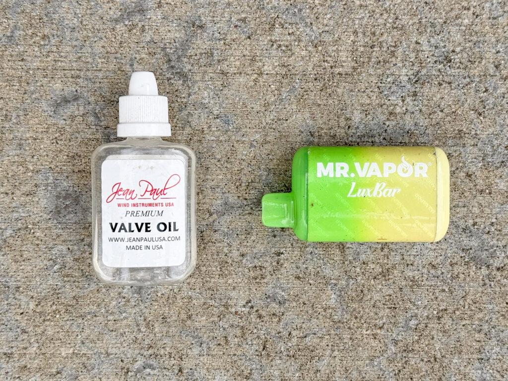 Small container of valve oil and Mr. Vapor LuxBar spent vape