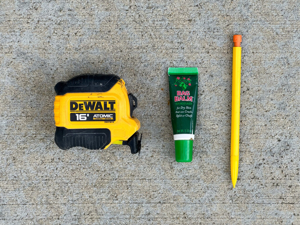 Damaged DeWalt 16' tape measure, a small tube of Bag Balm, and a yellow mechanical pencil